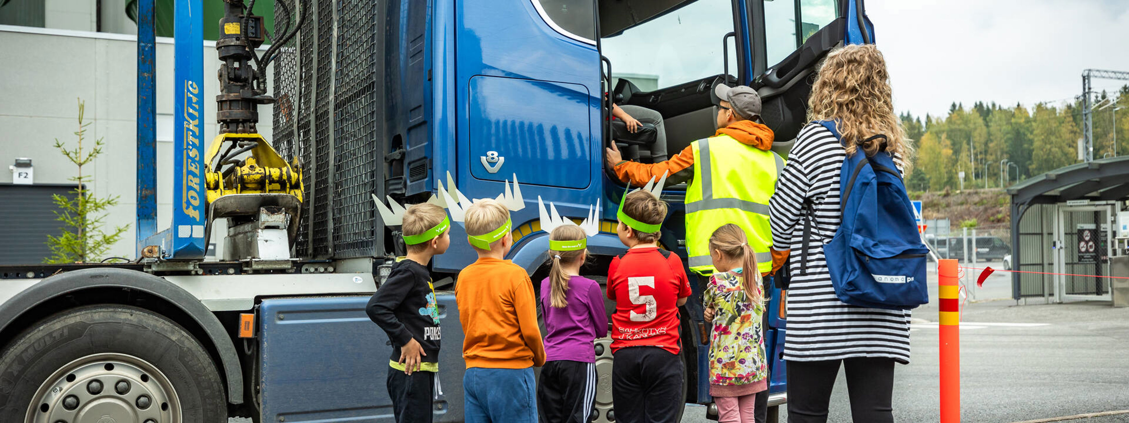 Lapset tutustuvat puutavara-autoon Metsä Fibren Äänekosken biotuotetehtaalla kuljettajan opastuksella.