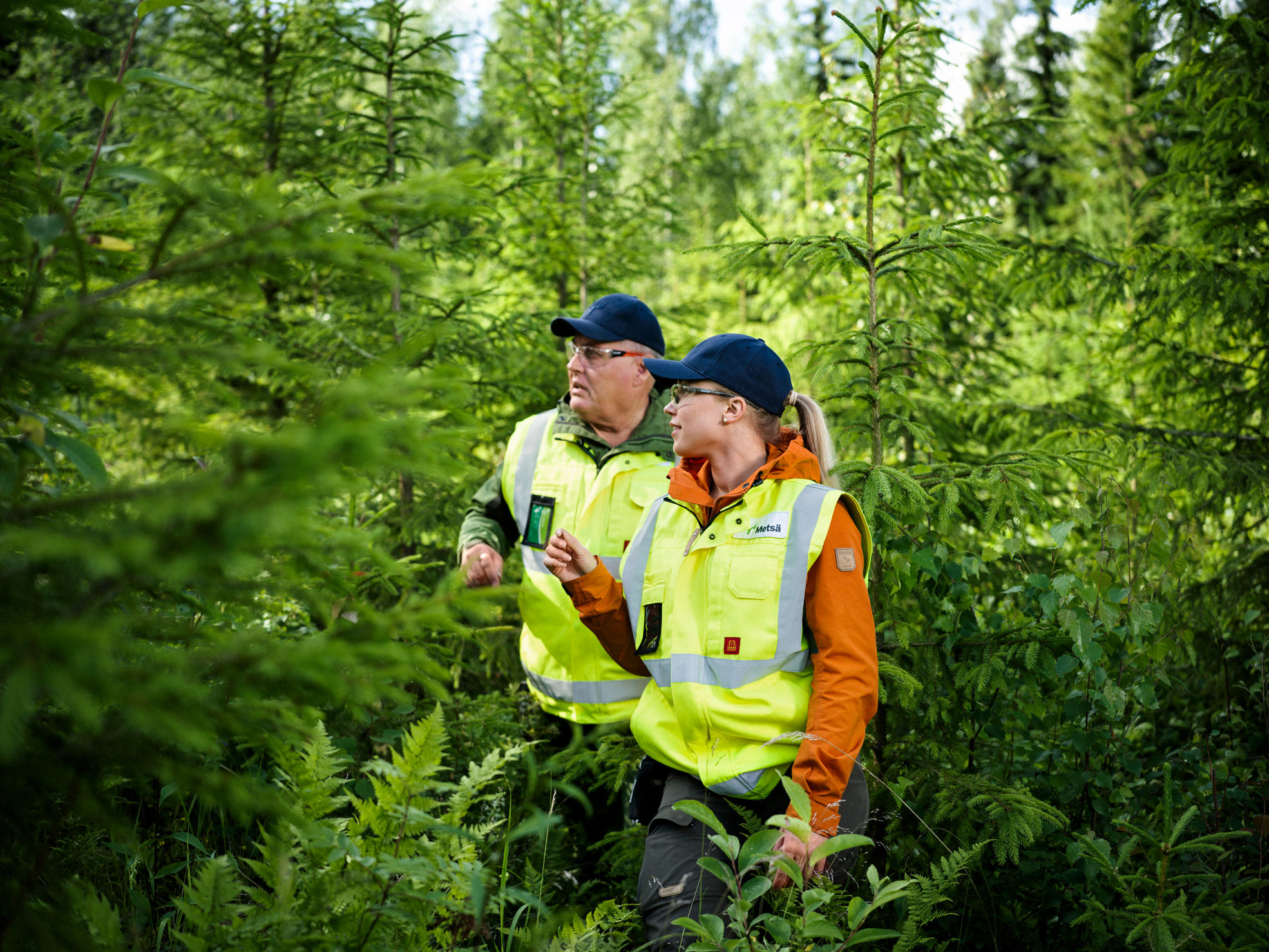 Skogsexpert och skogsägare går i skogen mot kameran.