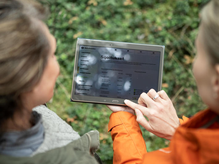A forest specialist and forest owner looking at Metsäverkko on a tablet.