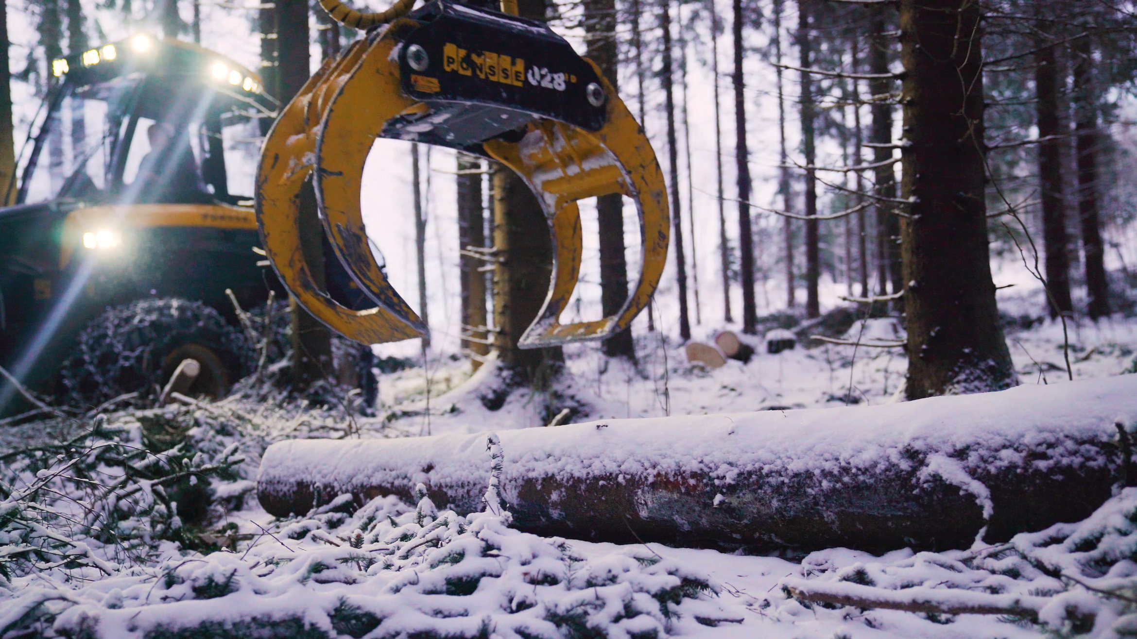 Skogsmaskin som greppar en stock.