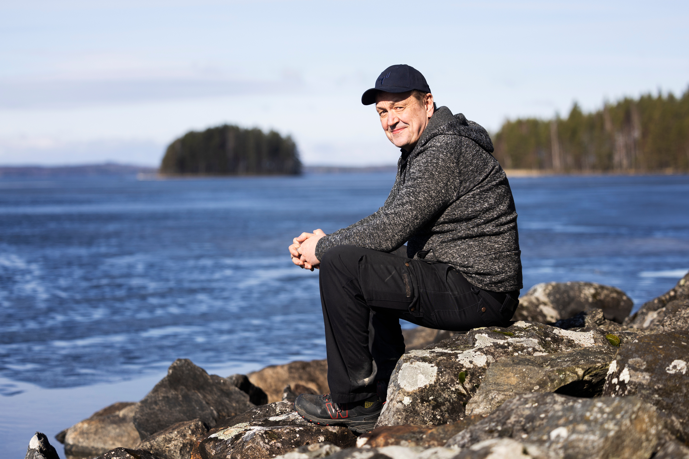 Juha Karhu sitter p&aring; en sten vid sj&ouml;stranden.