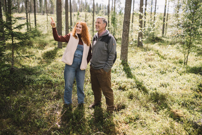 Father and daughter standing in the forest, looking where the daughter is pointing.