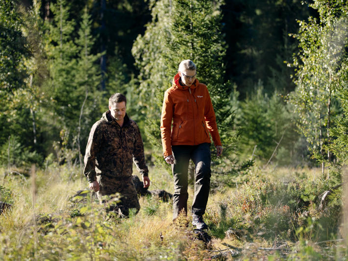Forest owner Juho and forest specialist Laura walking in the forest towards the camera.