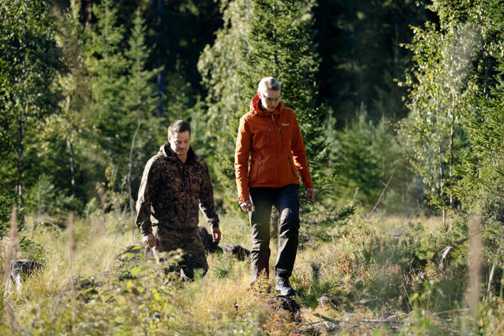 Forest owner Juho and forest specialist Laura walking in the forest towards the camera.