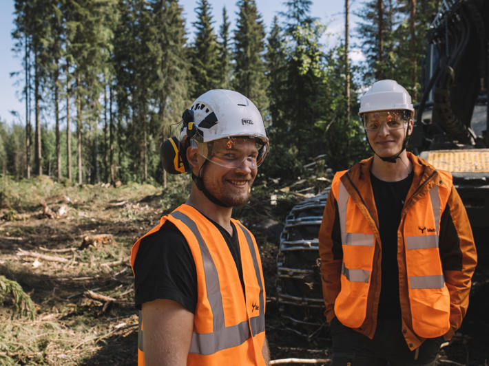 Korjuuyrittäjä ja Metsä Groupin operaatioesimies seisovat metsässä hakkuukoneen edessä.