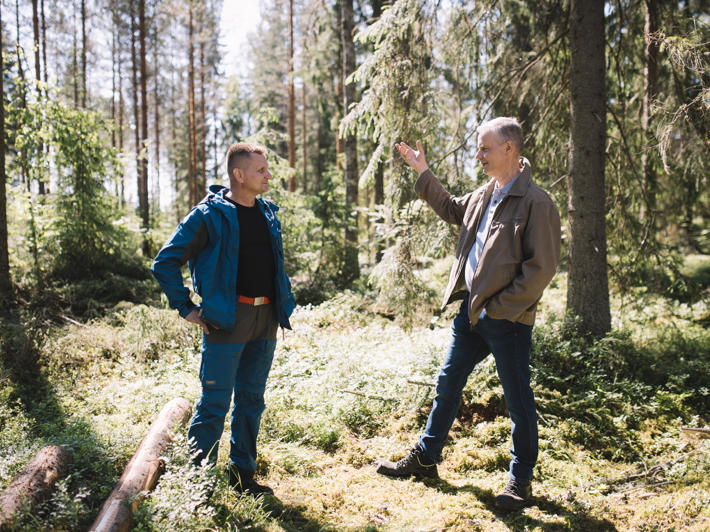 Metsäasiantuntija ja metsätalousyrittäjä keskustelevat metsässä.