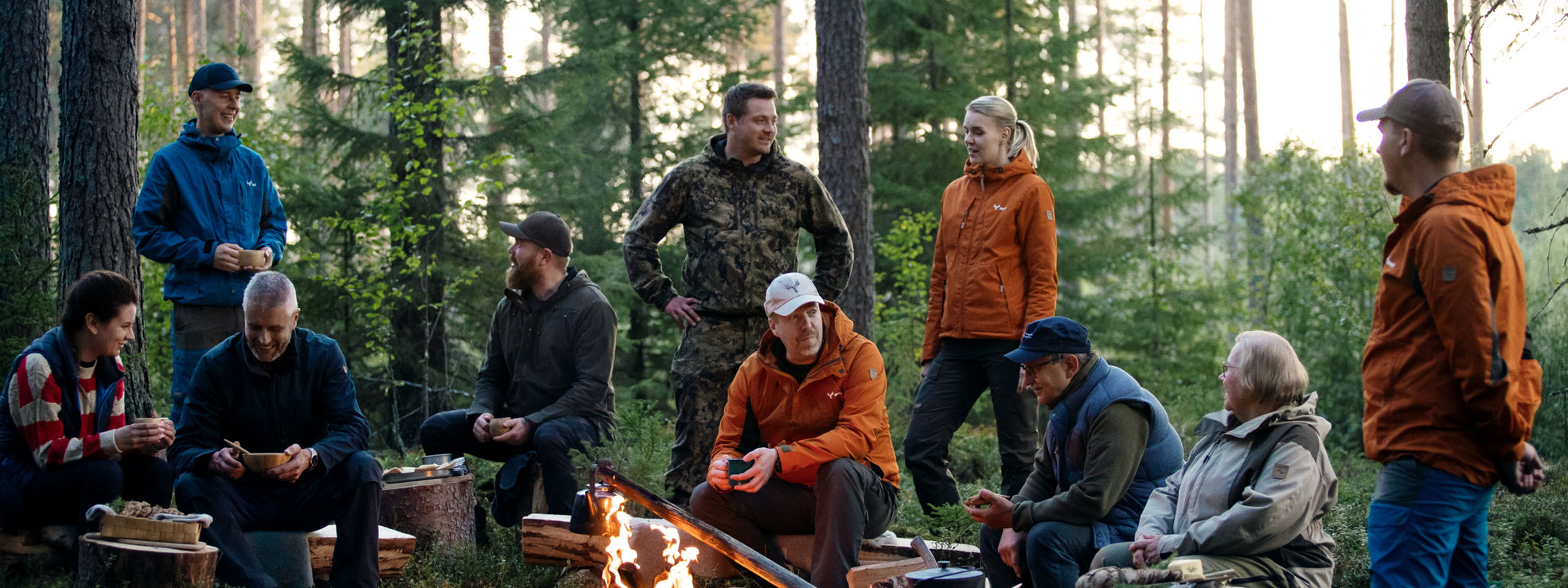 Owner-members drinking coffee and enjoying snacks around a campfire.