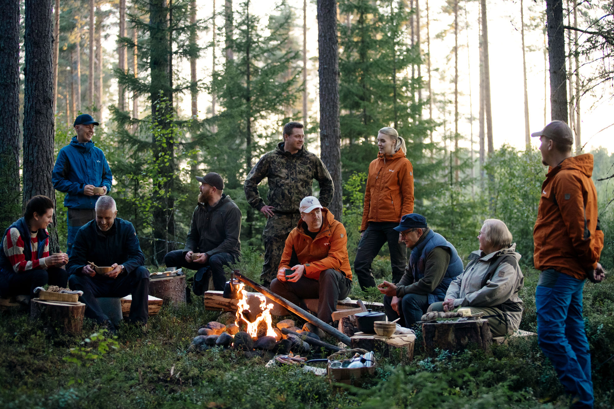 Owner-members drinking coffee and enjoying snacks around a campfire.