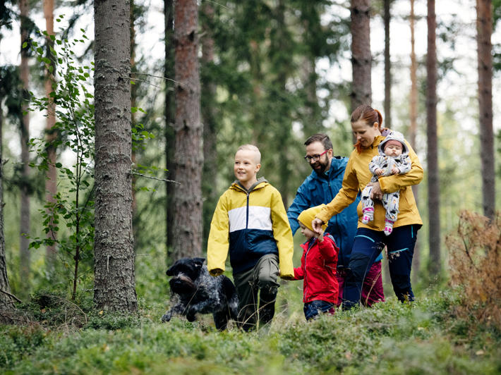 Barnfamilj på promenad i skogen.