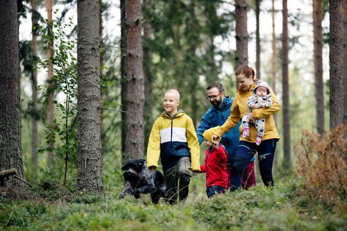 Barnfamilj på promenad i skogen.