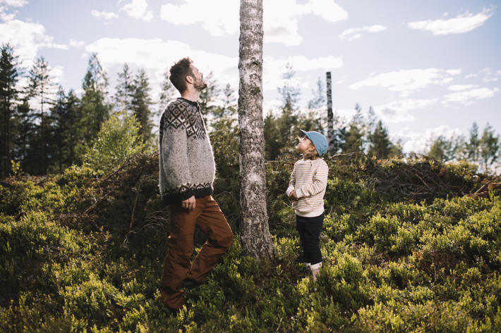 An adult and child look at a high biodiversity stump in a forest.