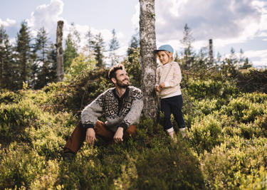 Mies ja lapsi metsässä tekopökkelön edessä.