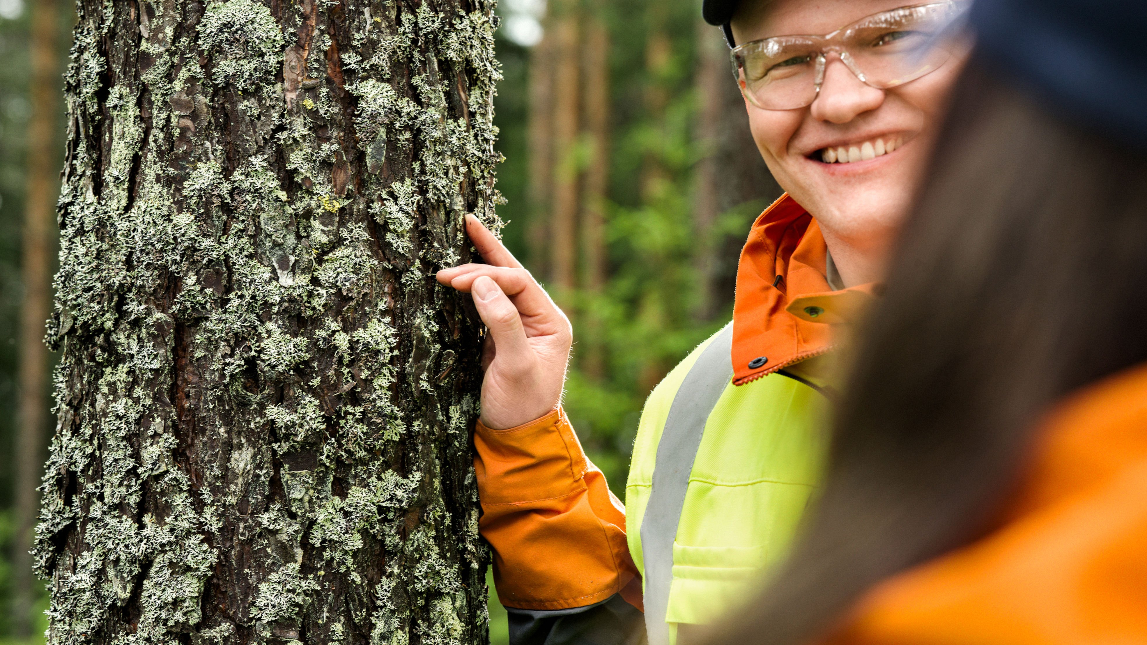 Metsäasiantuntija seisoo metsässä ja juttelee asiakkaalle.