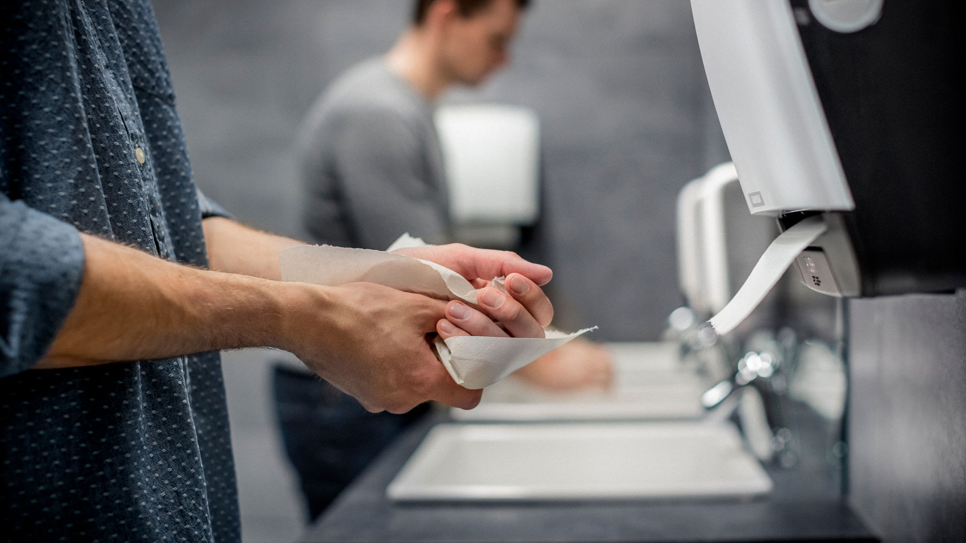 käsiä kuivattava henkilö julkisessa wc:ssä