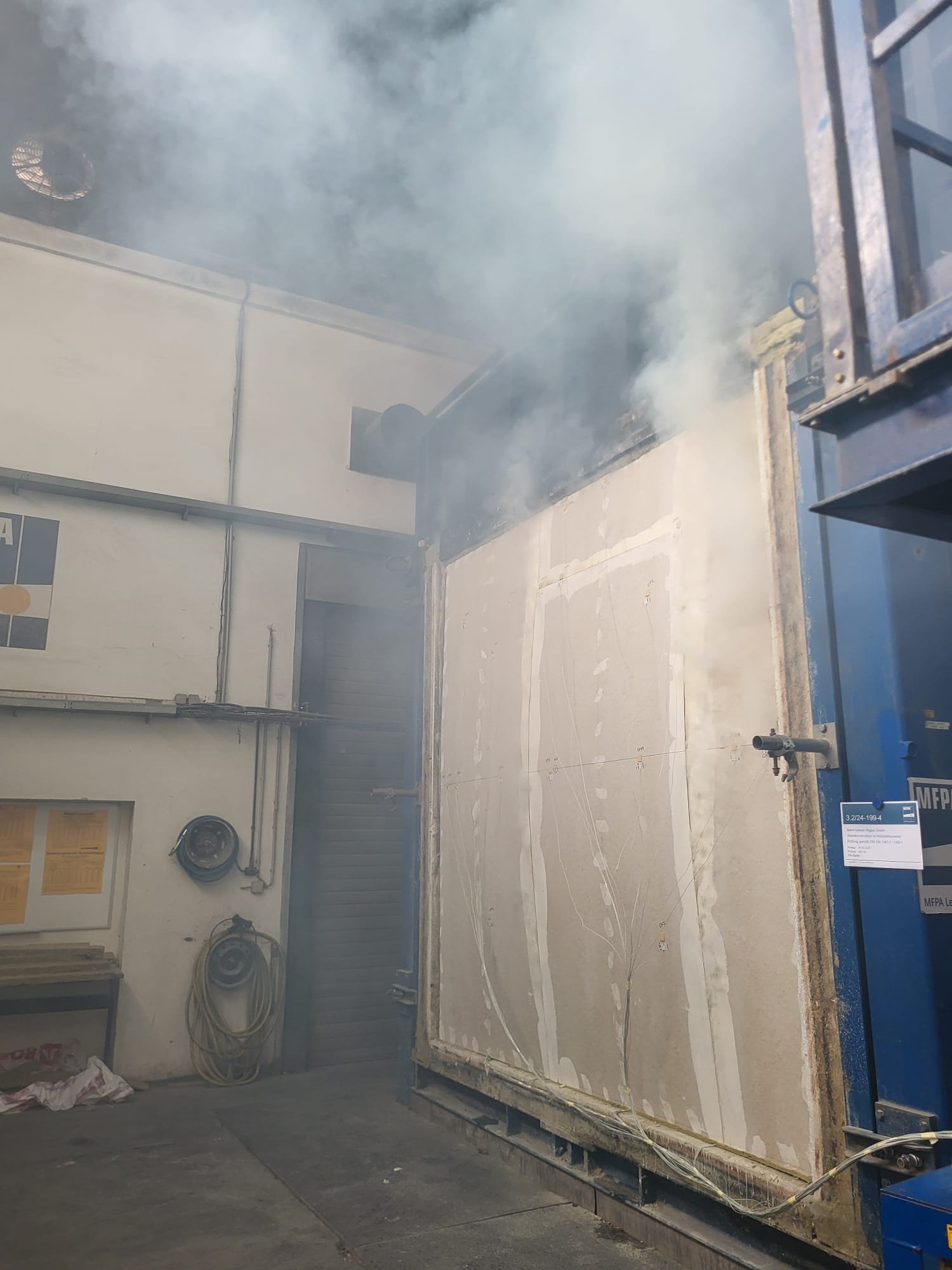 Ein gro&szlig;formatiges Wand&not;element wird im Pr&uuml;fstand beflammt, um den nach Katalog aufgebauten Kerto LVL Konstruktionen ihr reales Brandverhalten und die Einhaltung der geforderten Feuerwiderstandsklassen nachzuweisen.